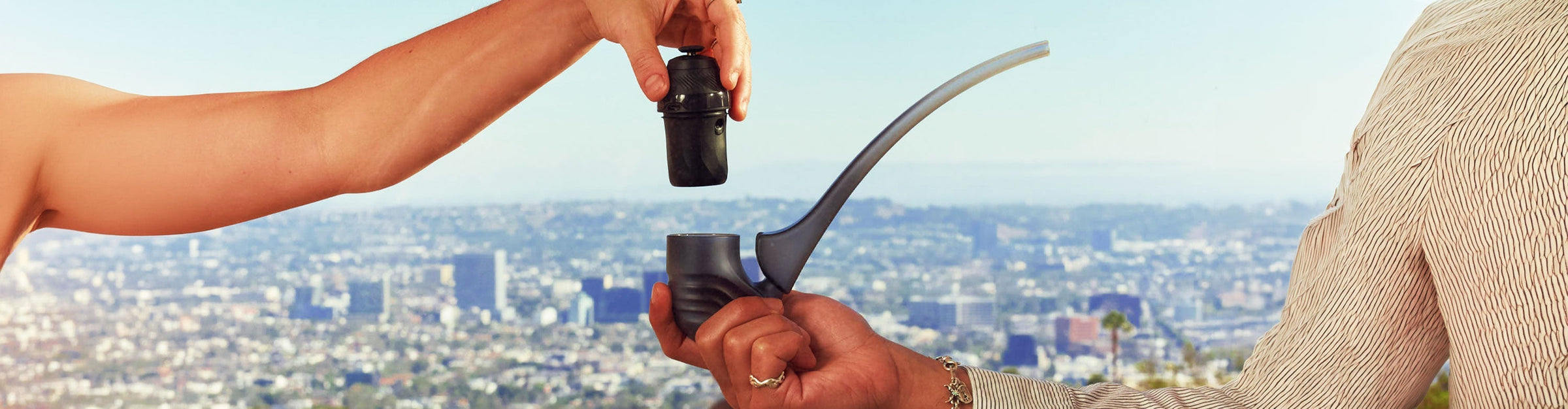 Two people holding Puffco New Proxy Wizard Attachment overlooking a cityscape